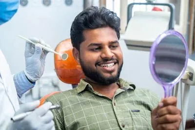 man taking a look in the mirror after getting a preventive checkup at Stonebriar Family Dentistry in Frisco, TX